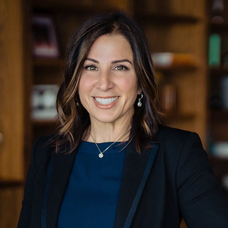 Headshot of Stacey Drabic, in front of bookshelves