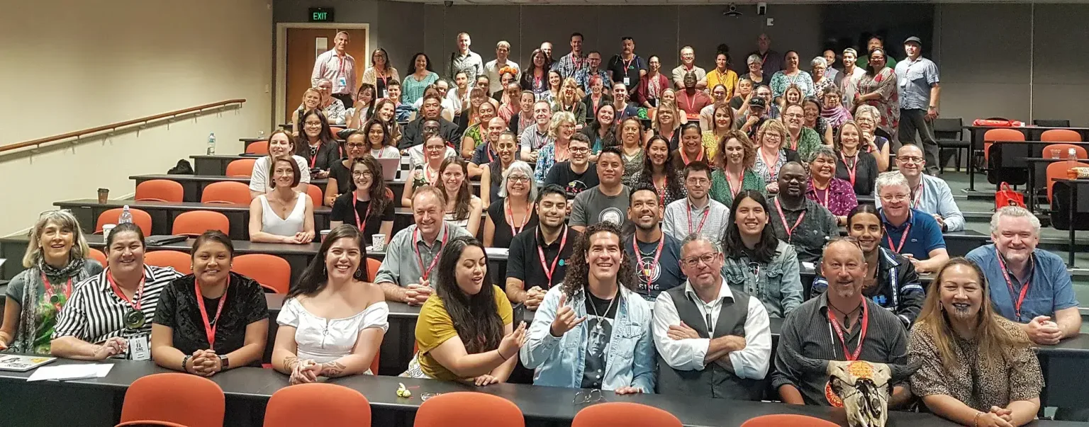 An amphitheater-style classroom full of smiling faces, about 100 people