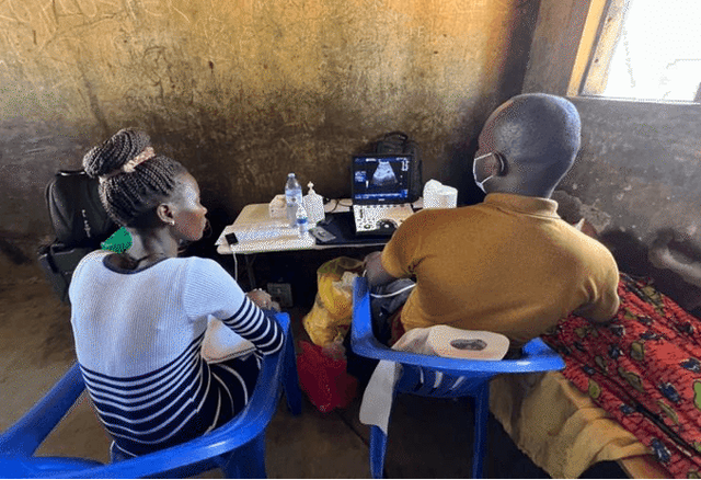 Liver ultrasound station in Pakwach, Uganda. Photo credit: Kaja Wasik A woman and a man sit at a desk looking at an ultrasound screen