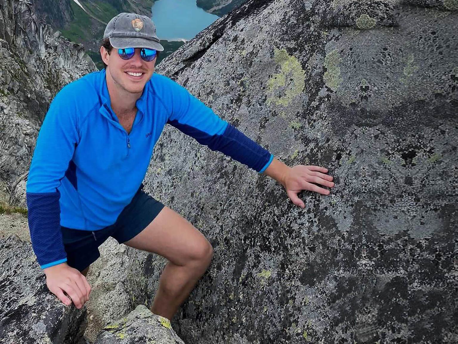 Tyler Standley climbing a hill with a body of water in the far distance.